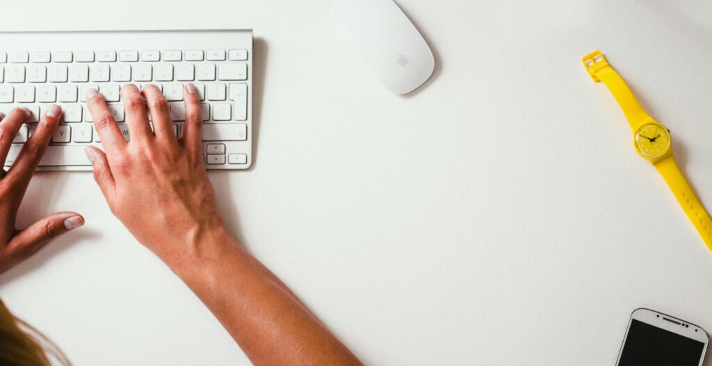 Mani su tastiera Apple wireless mentre si lavora alla creazione di un sito web