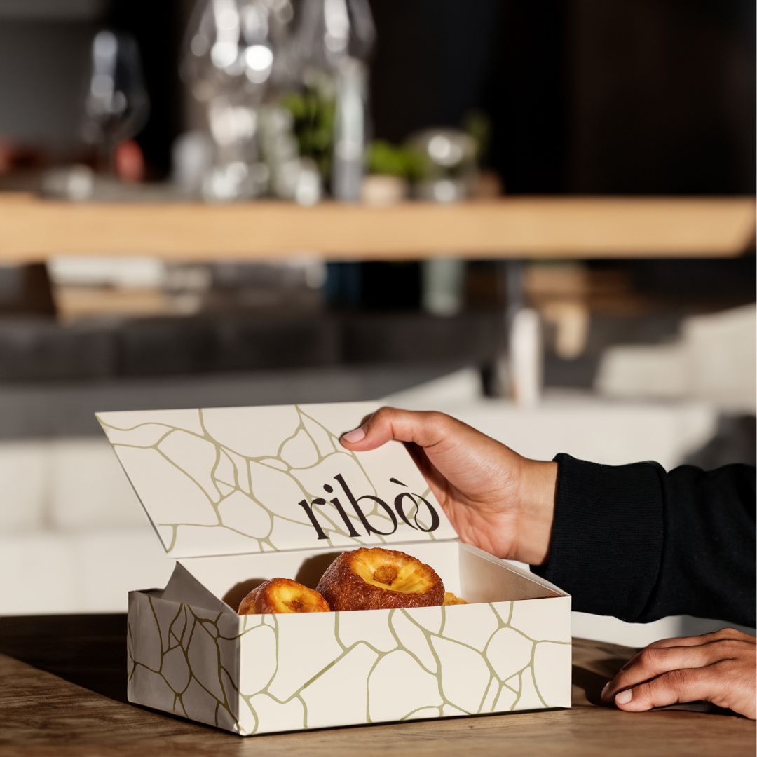 Scatola da asporto con logo Ribò e pattern ispirato al kintsugi, usata per prodotti da forno, rappresenta l’identità visiva del brand.
