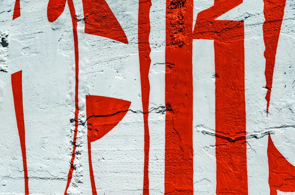 Dettaglio di parete ruvida con pittura rossa su sfondo grigio, esempio di design grunge 2025