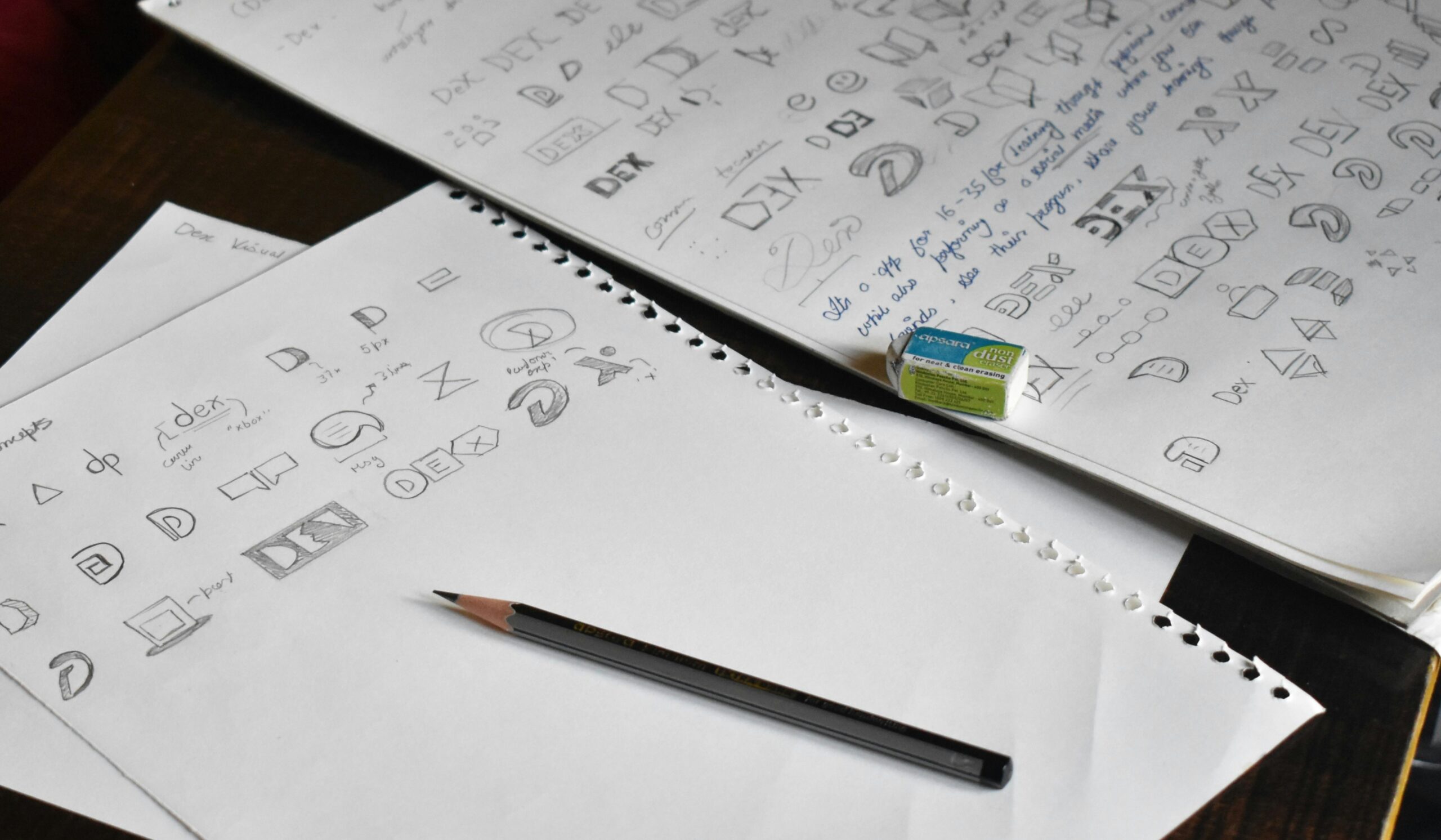 Schizzi e bozze di loghi disegnati a mano su fogli con matita, durante il processo creativo del brand design