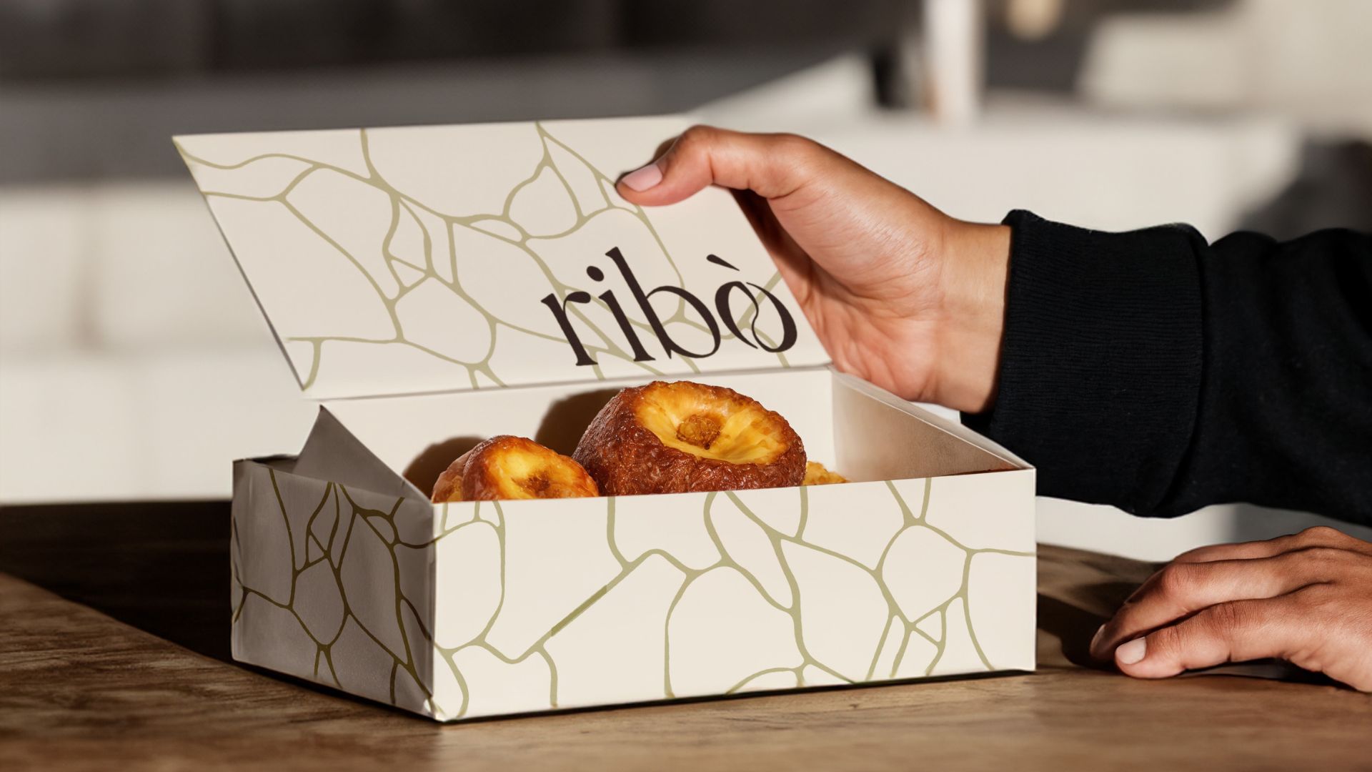 Scatola da asporto con logo Ribò e pattern ispirato al kintsugi, usata per prodotti da forno, rappresenta l’identità visiva del brand.