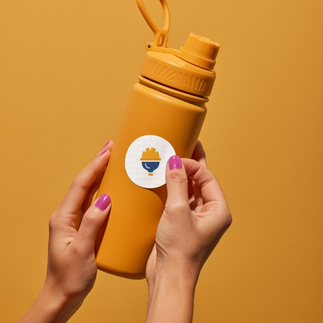 Mano che applica un adesivo con il logo Officina Sicura su una borraccia arancione, esempio di merchandising brand.