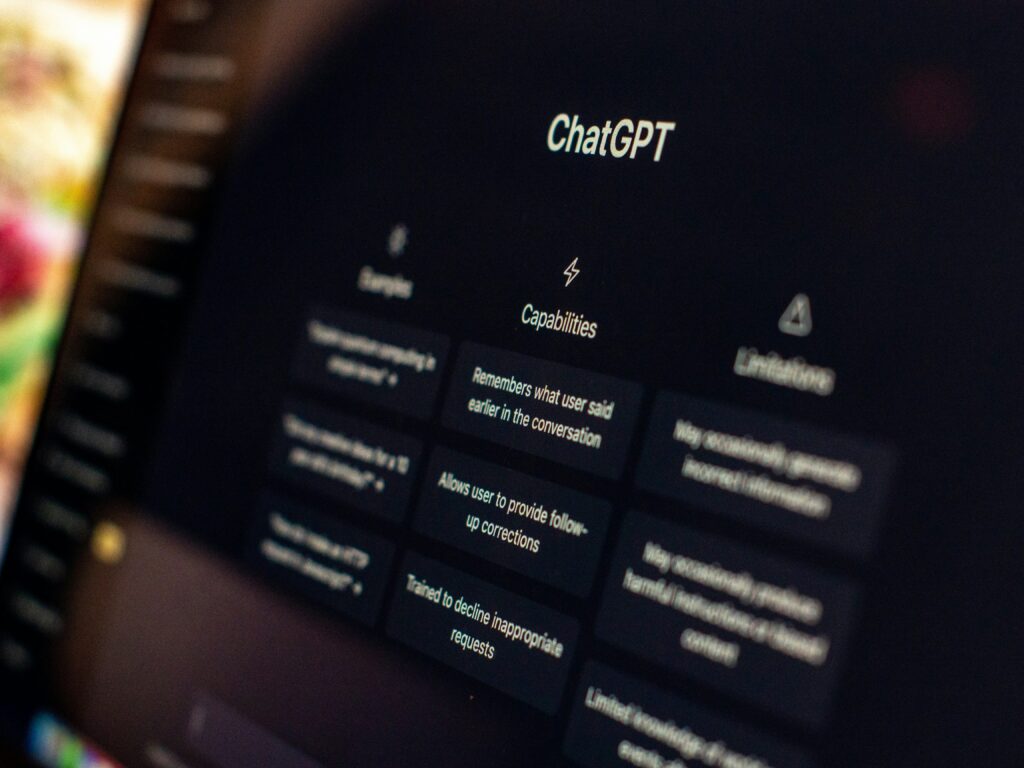 Mani su tastiera di un laptop che mostra ChatGPT, intelligenza artificiale applicata a contenuti e grafica.
