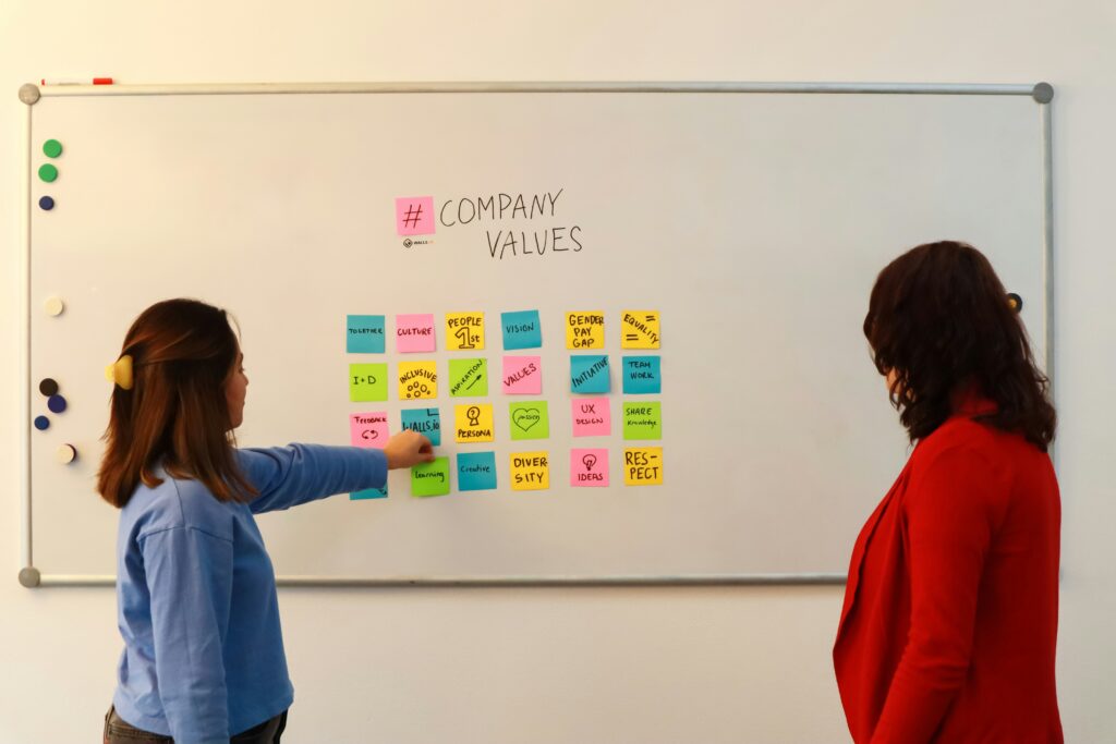 Designer che posiziona post-it su lavagna durante sessione di brainstorming creativo per sviluppare brand identity.
