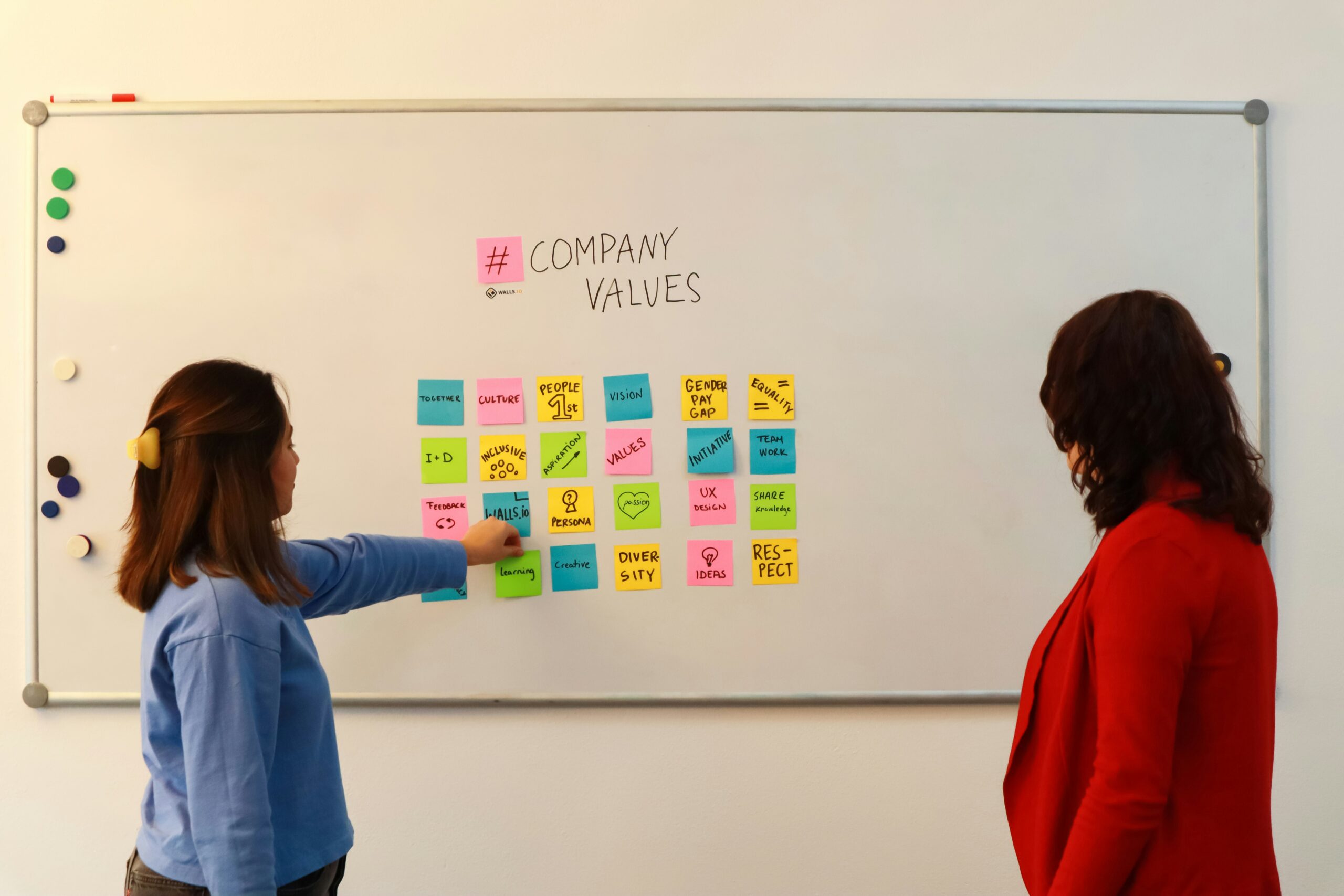 Designer che posiziona post-it su lavagna durante sessione di brainstorming creativo per sviluppare brand identity.