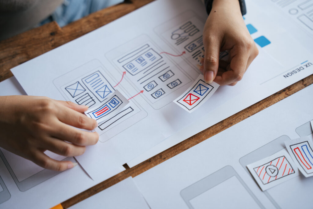 Mani che disegnano un percorso utente su carta come fase iniziale del processo di UX design