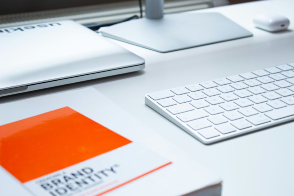 Scrivania minimal con libro Brand Identity e tastiera bianca, simbolo del processo di brand design per piccole imprese