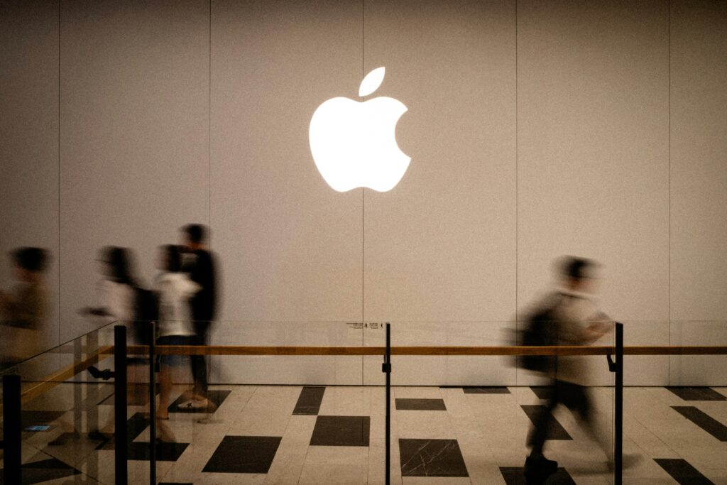 Persone che camminano davanti al logo Apple, simbolo di un brand con alta brand awareness e riconoscibilità globale.